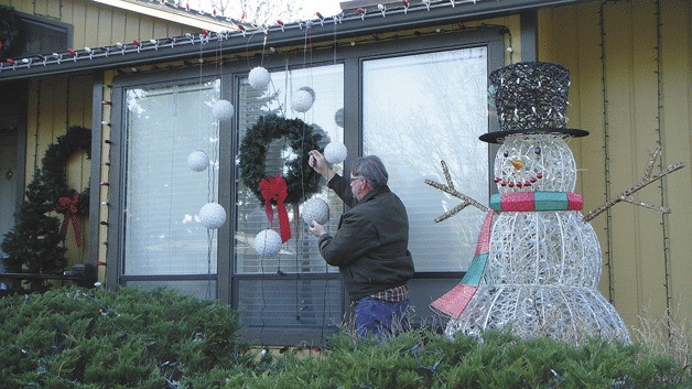 Bob McConnell hangs Christmas lights early this year.