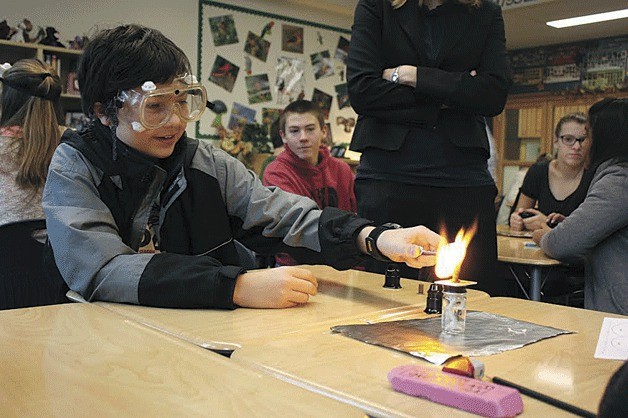 A student lights a small piece of paper on fire to see how it burns as part of a science lesson at Stella Schola Middle School.