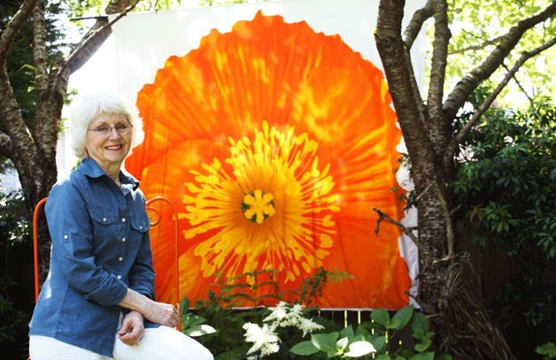 Marilyn Knapp painted an old duvet cover with a picture of a poppy flower. The cover is pinned in her backyard as the centerpiece of her garden.