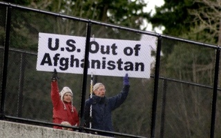 Kirkland residents Todd Boyle and Margie Ostle wave a sign about Interstate 405 on a recent morning that states their opposition to the US military presence in Afghanistan.