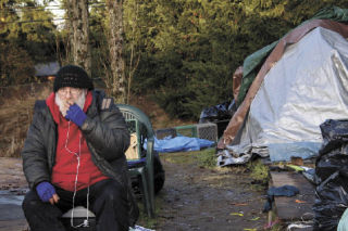 Tent City 4 resident Dennis Peters takes a cigarette break during the encampment’s move from Kirkland’s St. John Vianney to Woodinville on Saturday