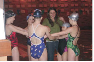 Coach Jay Bloser shares a laugh with her swim team members at St. Edwards Pool. ANDY NYSTROM