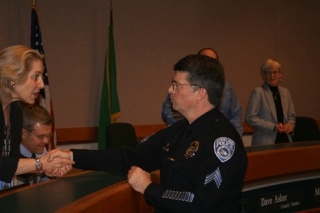 Councilmember Jessica Greenway shakes Kirkland Police Sgt. Pat Gallagher’s hand in honor of his 30 years of service.