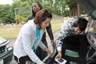 Northwest University junior Teresa Garcia (left) and senior Jason Hatcher help new student Kaila Hammond move her belongings from her car to her dorm room.