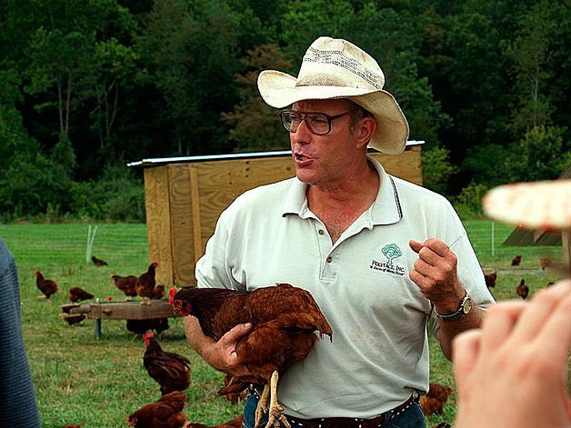 Self-described lunatic farmer Joel Salatin holds a hen during a tour of his family's farm