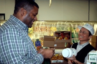 Greenline Organic Health owner Kuang Lin (right) hands a container of supplements to regular customer