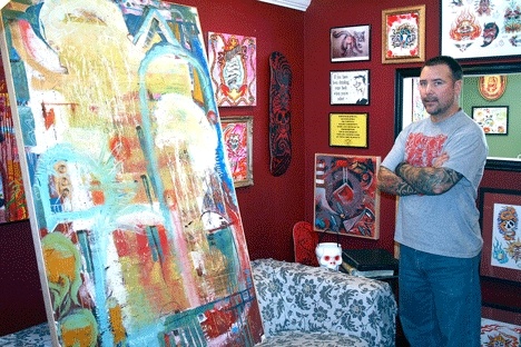 Local artist Dave Richmond stands next to one of his oil paintings inside his business