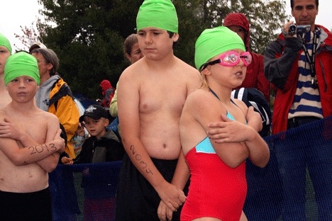 Swimmers show the affect of cold and rainy conditions as they wait for the race to begin Saturday.