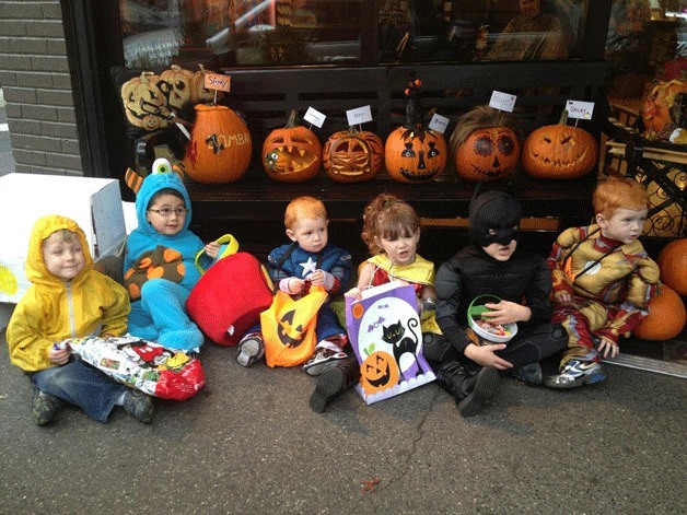 Young trick-or-treaters line up in front of Bombaii Cutters in downtown Kirkland on Halloween for some tasty treats.