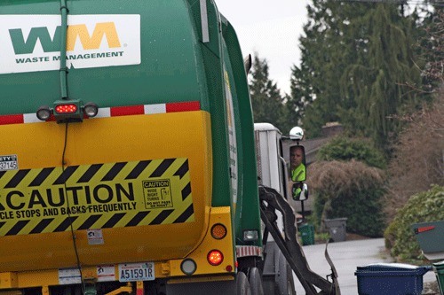 Waste Management employee picks up the garbage in the Houghton neighborhood of Kirkland on Monday.