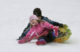 Megane Kyes and Samuel Hu grimace as they land a jump while sledding down the hill at the North Kirkland Community Center Park on Tues.