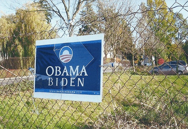An Obama-Biden sign is padlocked to a fence.
