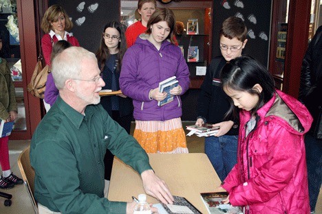 Guest author Ben Mikaelsen signs a copy of his book for Rosa Parks 4th grader Michelle Yang (right) during a young author's event at Benjamin Franklin Elementary Saturday. Also pictured is Wilder Elementary 5th grader Chloe McDonell (left) and Rosa Parks 4th grader Julian Guthrie (center).