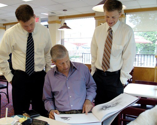 Kirkland author Dennis Dunn shows Caleb Harris (right) and Paul Chatterton (left) photos and illustrations from his book; “Barebow