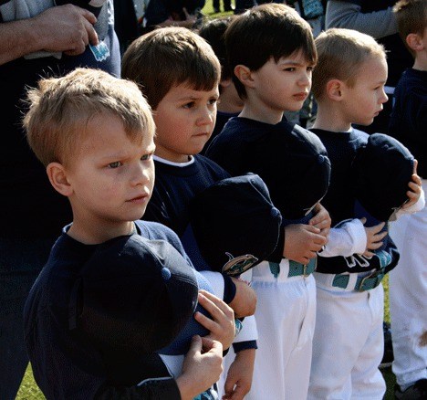 Kirkland American Little League players of the Raptor's team take their hats off as they listen to the National Anthem during the opening ceremony for the 2010 season at Lee Johnson Field Saturday. Left to right