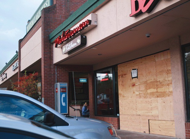 A sign posted on some boards covering the storefront at the Mediterranean Kitchen in Kirkland states 'Will be open again soon