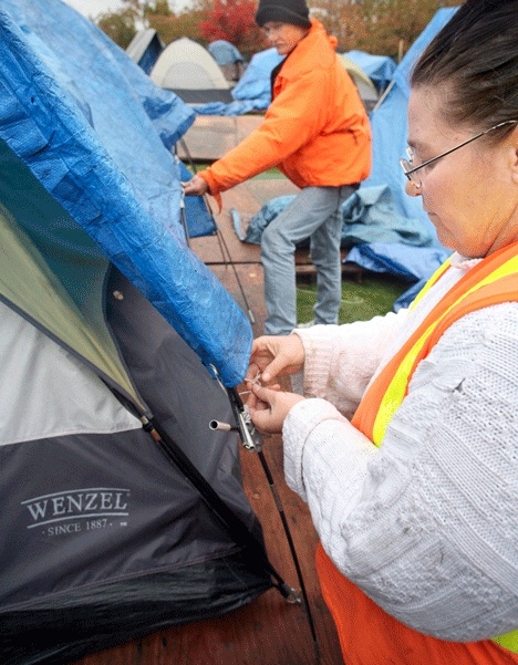 Debra and Jack Exum work to secure a tarp over their tent to keep the rain out at Tent City 4 last November