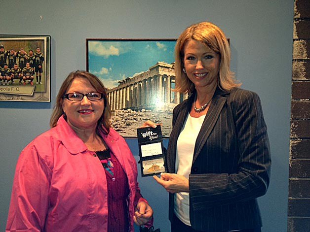 Kirkland Reporter sales representative Janeen Archer presents a $100 Acropolis Pizza gift card to Diane Gilbery