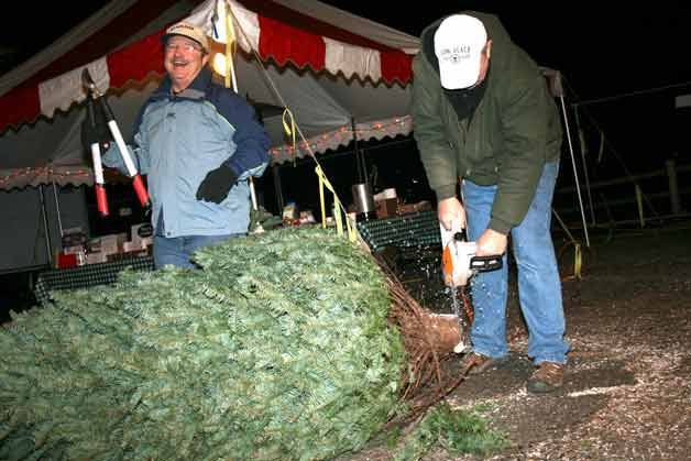 Kneal Hollander laughs at his friend and Kirkland Kiwanis president Ralph Loveland as he cuts down the base of a recently purchased Christmas tree.