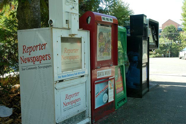 Newspaper boxes are lined up along the sidewalk at the Kirkland Post Office