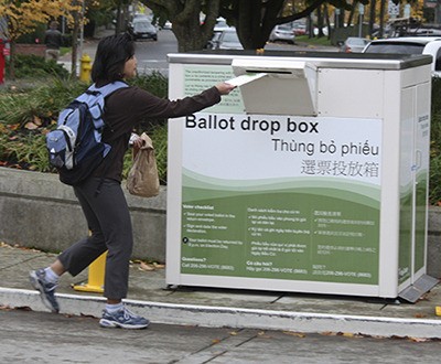 A King County voter submits her ballot for the 2014 general election at Redmond City Hall.