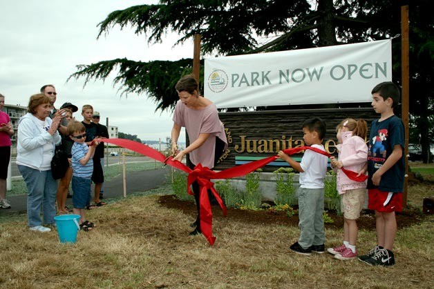 Councilwoman Amy Walen cuts the ribbon in front of the Juanita Beach Park sign during a re-opening celebration at the park Aug. 5. The park closed in May 2010 for renovation work.