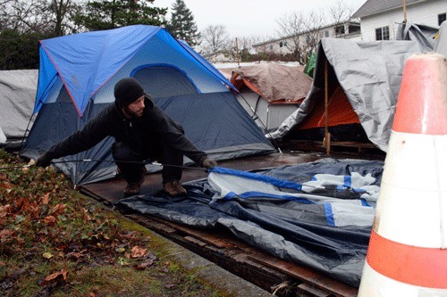 Tent City 4 resident Alan Erickson puts up a tent at the homeless encampment that moved into the parking lot of Kirkland Congregational Church on Saturday