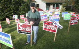 Rep. Larry Springer (D) stands among a sea of signs in his front yard Nov. 5.