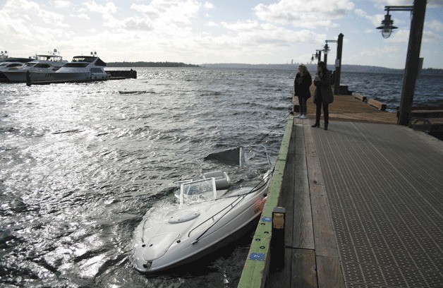 Spectators look on at the sunken boat off of Kirkland marina.