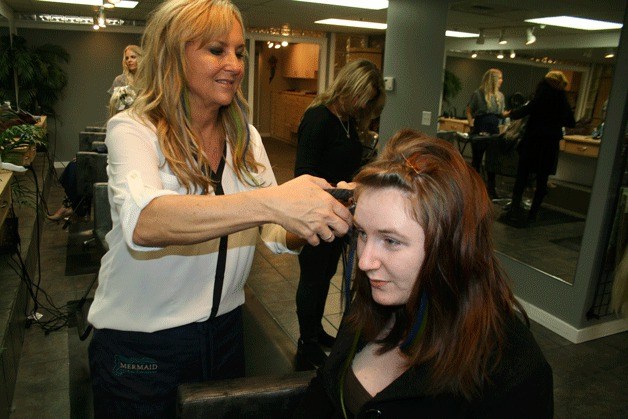 Mermaid Hair Extensions owner Cindy Reynolds applies Seahawks blue and green hair extensions to a customer's hair.