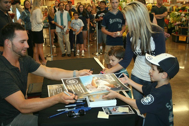 Seattle Mariner Casper Wells signs a poster for Austin and Ryden Rapoza at the Kirkland Fred Meyer on Thursday as their mom watches on.