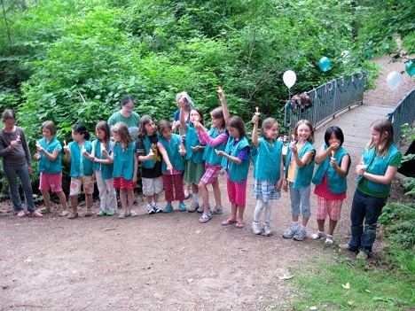 Fly up! Members of Peter Kirk Elementary's third grade Girl Scout Brownie troop celebrate as they complete their 'fly up' ceremony to Junior Girl Scouts after crossing the bridge in the woods behind the school recently. The 14-member troop has performed many community service projects.