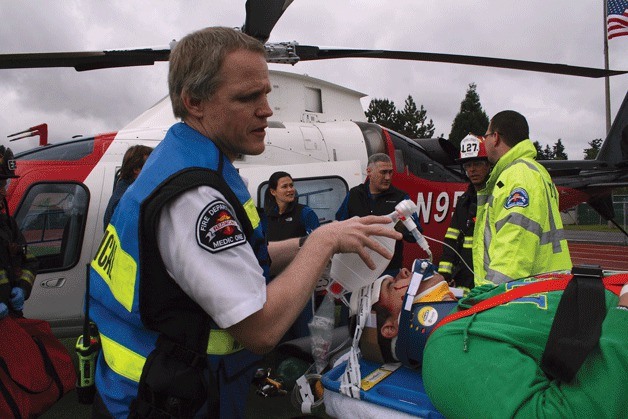 A Medic One responder assists Lake Washington High School senior Alex Lemme as a crew prepares to mock airlift the student into a helicopter at the school's football field on Friday morning. The event was part of a DUI vehicular homicide simulation that the school has participated in for the past 15 years.