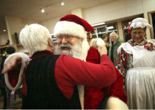 Santa reaches out to hug Rebecca Willow during a holiday celebration to benefit KITH at Parkplace Books.