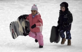 Emily Flagg and Shane Ahrens carry their sleds back up the hill for another go at the North Kirkland Community Center Park on Dec. 23