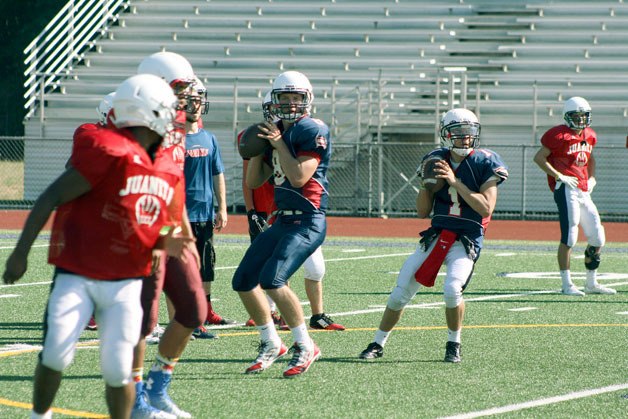 Rebel quarterbacks practice during a preseason workout at Juanita High School last week.