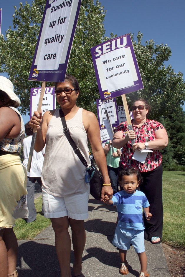 EvergreenHealth worker Sokha Hammond and young Kai Hour participate in a picket of the hospital on Thursday over staffing and the CEO's pay raise.