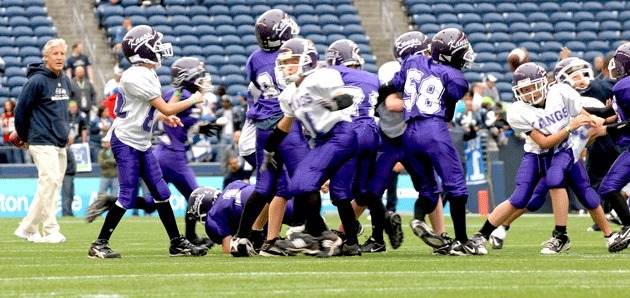 The Lake Washington Kang Cubs White team holds a scrimmage against the LW Kang Cubs Purple team at Qwest Field as Seahawks' coach Pete Carroll looks on before the Seahawks game Sunday.