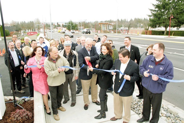 Kirkland City Council members and city officials hold the ribbon while Mayor Amy Walen cuts it during a ceremony to officially finish one of the biggest road construction projects in Kirkland history. The 85th Street corridor project helped improve many aspects of the popular thoroughfare