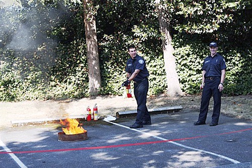 Firefighters Doug Tomczak and Ken Weihs demonstrate to residents how to use a fire extinguisher during the fire fair.