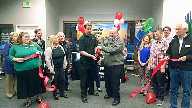 Kirkland City Councilman Toby Nixon helps with the ribbon cutting at Kirkland's newest business SpeedPro Imaging on Thursday.