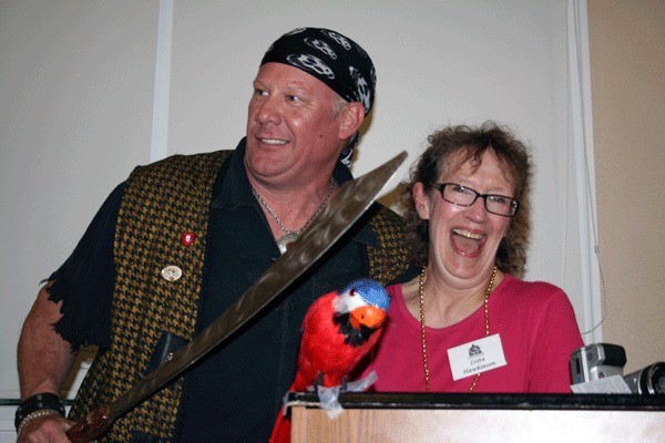 Seafair Pirate Chas Anderton takes Kirkland Heritage Society President Loita Hawkinson captive for a moment during a visit to a Heritage Society meeting June 29.