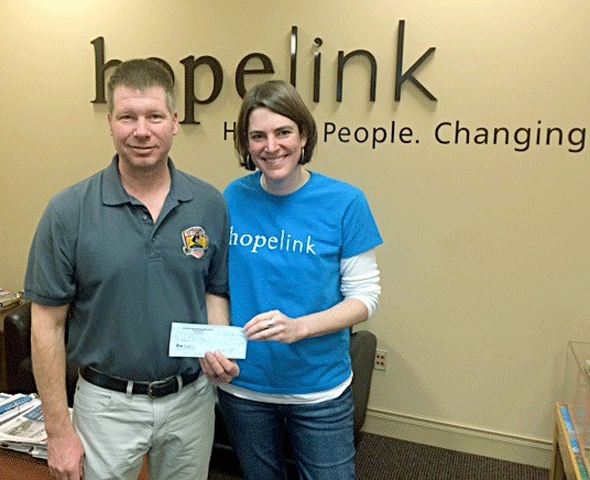 Kirkland Fire Capt. Greg Picinich presents a Hopelink staff member with a check for $1