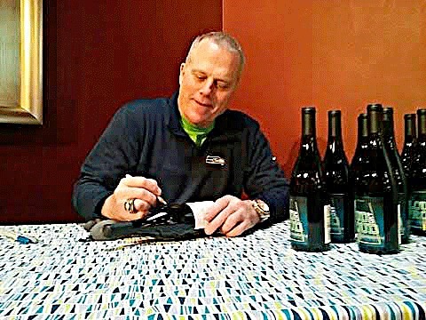 Former Seahawk kicker Norm Johnson signs bottles of his new wine in Kirkland.