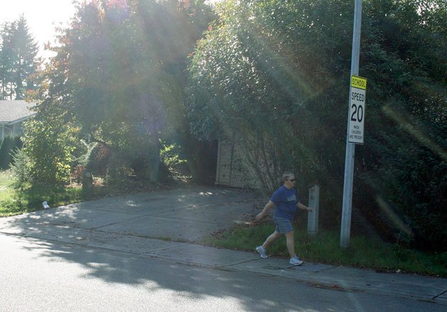 A house in the Juanita neighborhood was the epicenter for a SWAT raid on Oct. 4. The house can be seen here shrouded in the trees and bushes while a neighbor walks along the sidewalk by a school zone sign. The home is 300 feet away from Helen Keller Elementary.