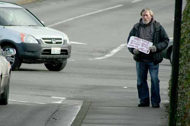 A panhandler stands at the intersection of Northeast 124th Street and 116th Avenue Northeast in the Totem Lake neighborhood on Friday seeking money from strangers.