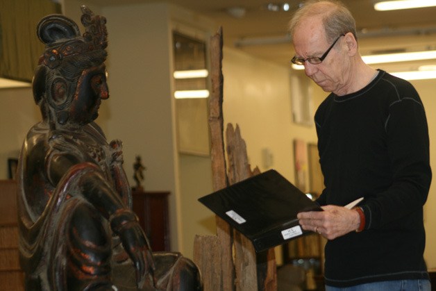 Gallery owner Jim Russell catalogs a new piece his business received from China.