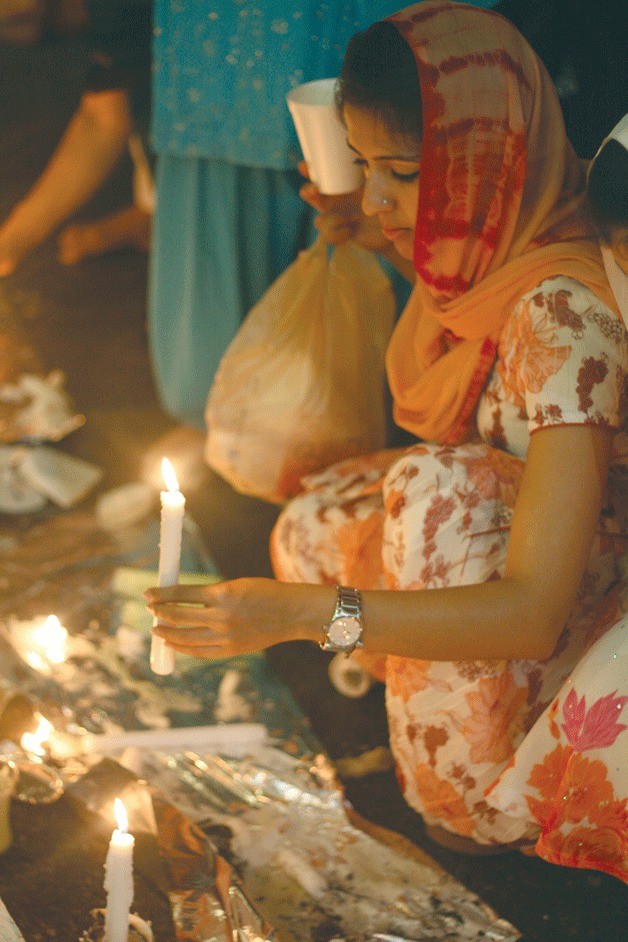 Sonia Kaur arranges candles at a vigil on Saturday night at the Sikh Centre of Seattle in Bothell.