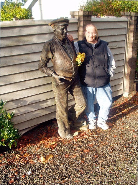 Anita Maxwell stands next to a statue of her great uncle Frank Gilbert
