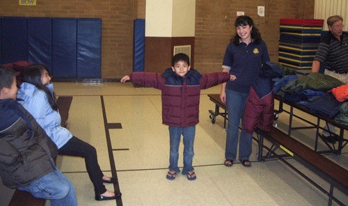 Rotarian Elizabeth Rusnak suits up a John Muir Elementary student with a new coat.